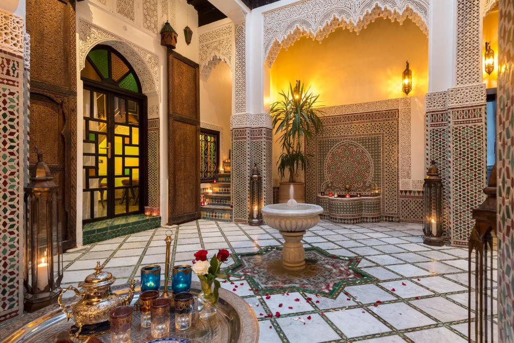 a lobby with a fountain in the middle of a building at Algilà Fes Riad Medina Charme Hotel in Fez