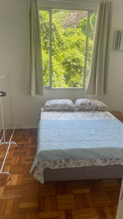 Hotel Aconchego de Copacabana, a bed in a room with a large window at Aconchego de Copacabana in Rio de Janeiro