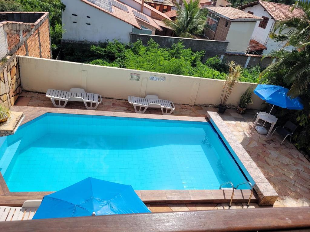 una gran piscina azul con 2 sillas y sombrillas en Pousada Betta, en Pirenópolis