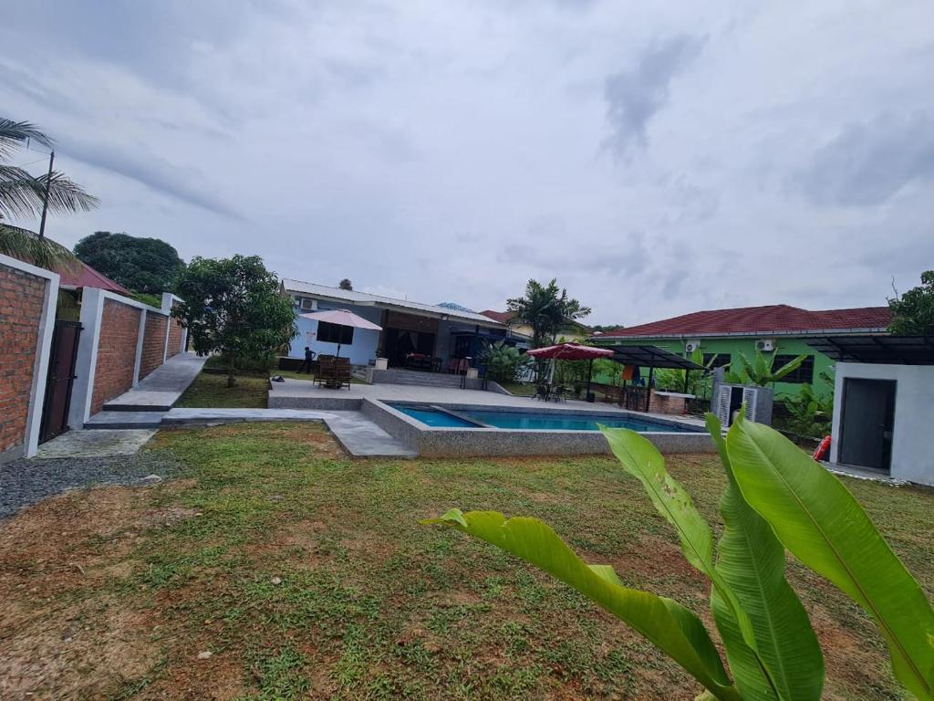 D'Camp Homestay with swimming pool في Kampong Kenangan: منزل فيه مسبح في ساحة