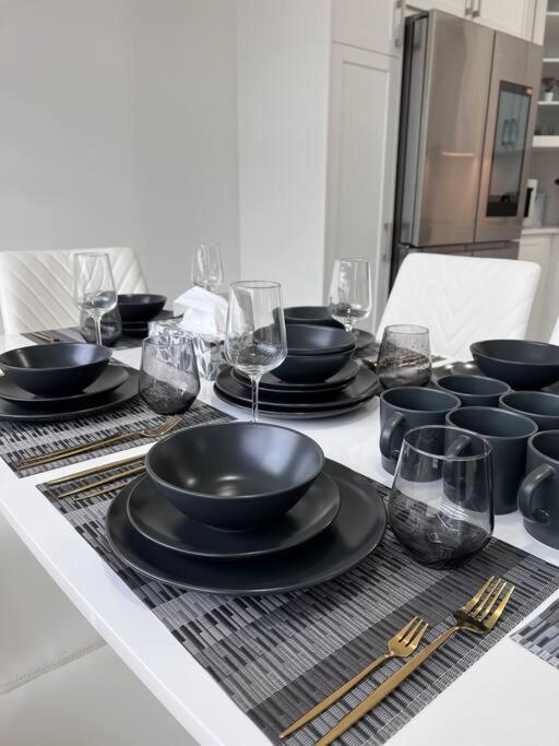 una mesa con tazones negros, platos y vasos en Brand New 4 bedroom Villa by Hamilton Airport! en Hamilton