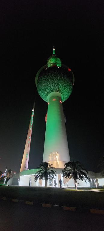 a building with a green tower at night at Aladdin hostel in Kuwait