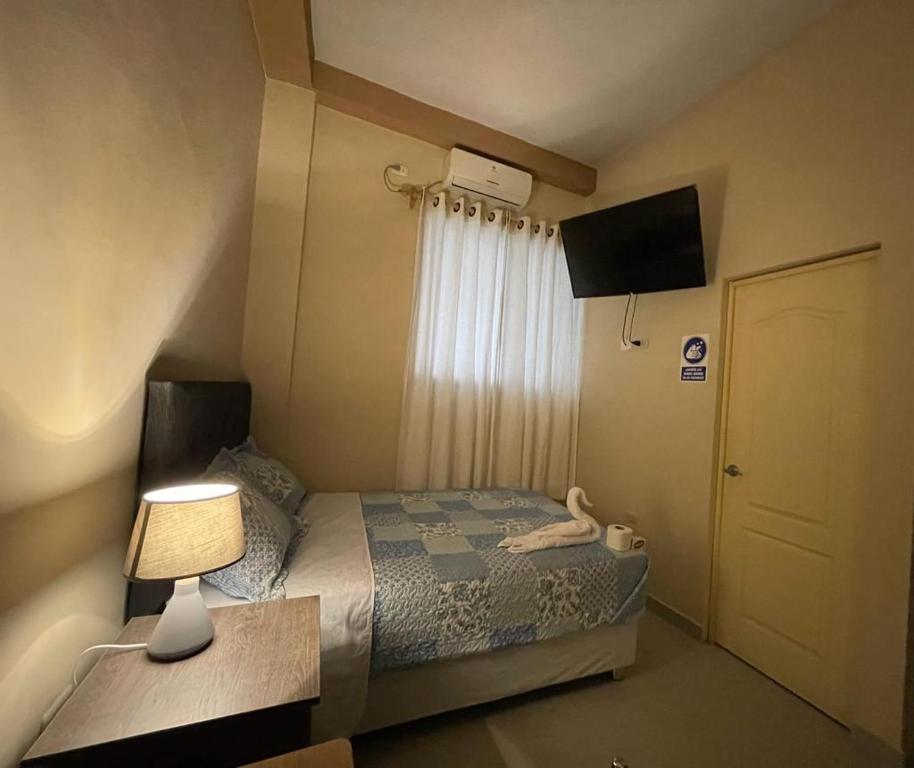 a bedroom with a bed with a lamp and a window at La Pequeña Suiza in Talara