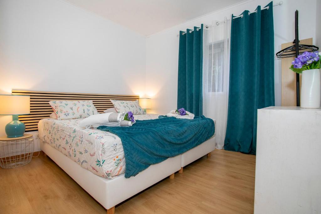 um quarto com uma cama grande e cortinas azuis em Casa da Belinha em Ponta Delgada