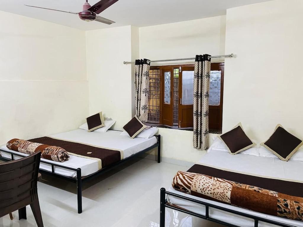 a bedroom with two beds and a window at Naivedyam villa in Mount Ābu