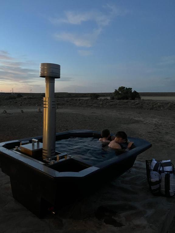 a couple of people in a hot tub on the beach at Traka Cottage in Prince Albert
