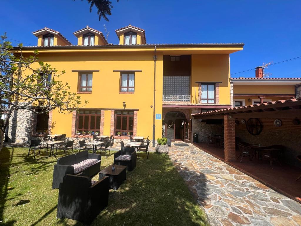 una casa amarilla con mesas y sillas en el patio en Hotel Gavitu, en Celorio