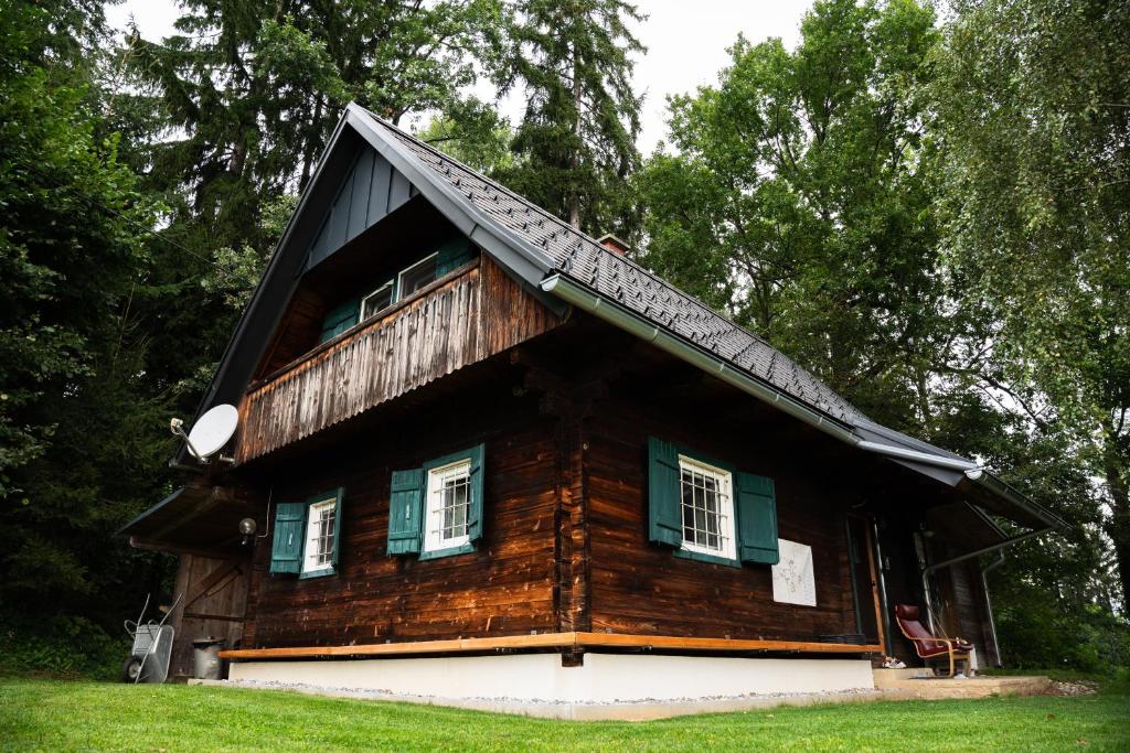 Cabaña de madera con ventanas con contraventanas verdes en Gregor's Ferienhaus im Wald, en Edelschrott