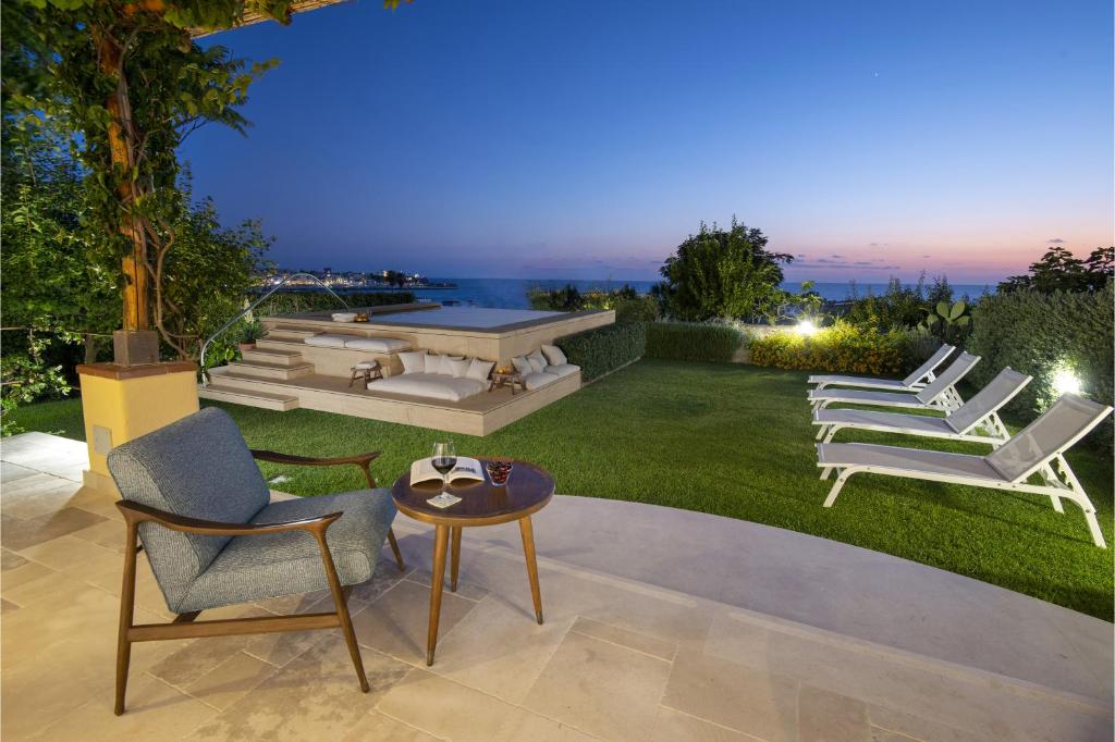 eine Terrasse mit Liegestühlen, einem Tisch und einem Tisch in der Unterkunft OraBlu Executive Villas in Ischia