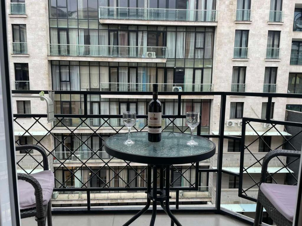 a table with a bottle of wine and two glasses on a balcony at Paliashvili 90 - VAKE Park 2BR Apartment in Tbilisi City