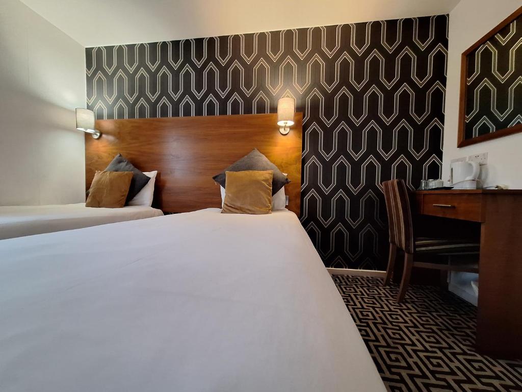 a hotel room with a bed and a desk at Stockwood Hotel - Luton Airport in Luton