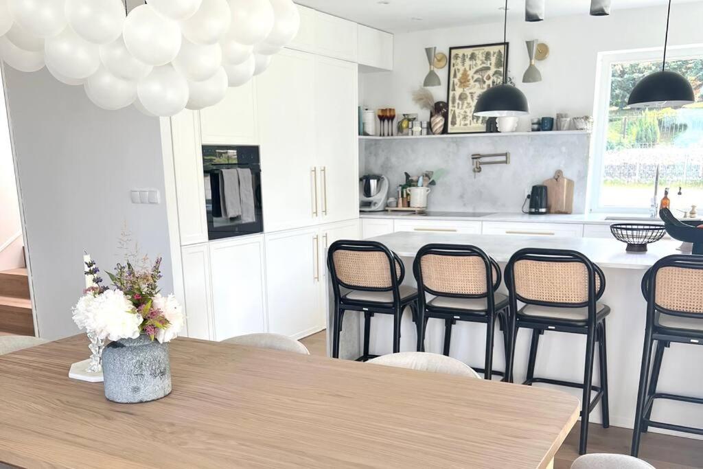 eine Küche mit einem Holztisch mit Stühlen und eine Küche mit weißen Schränken in der Unterkunft Dom z widokiem na góry stołowe i dużym ogrodem in Kłodzko