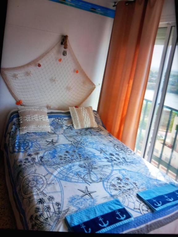 - un lit avec une couette bleue et blanche et une fenêtre dans l'établissement Studio plage karina, à Empuriabrava