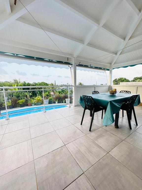 a patio with a table and chairs and a pool at Demeure vue mer avec piscine privée in Petit-Bourg