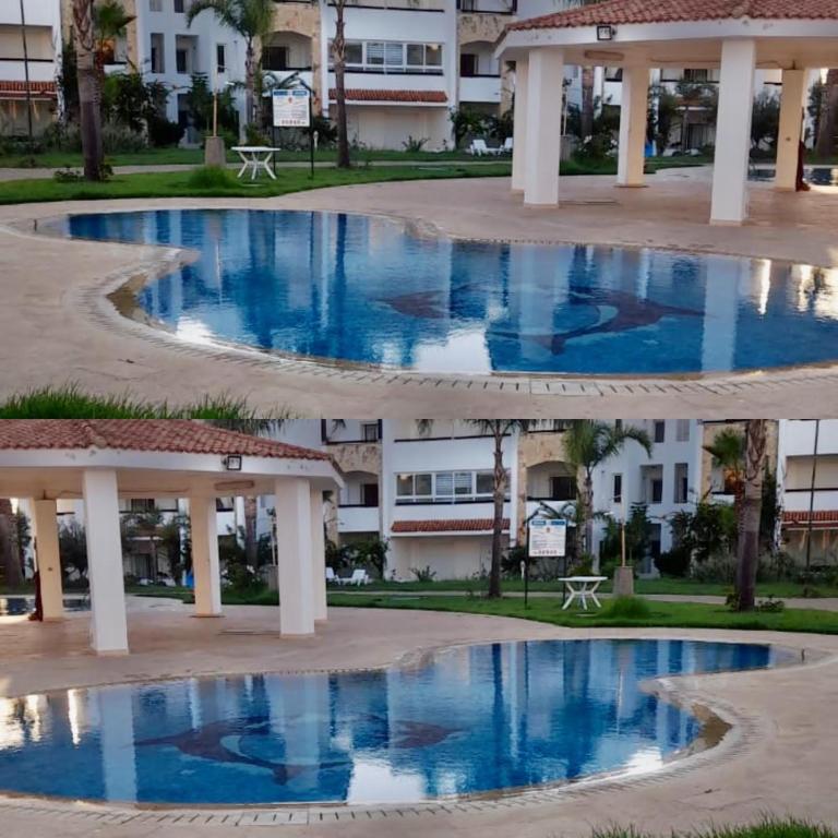 a pool in front of a building with blue water at Marina Golf appartement de luxe in Asilah