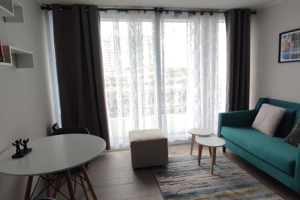 sala de estar con sofá azul y mesa en Departamento nuevo y cómodo en Santiago