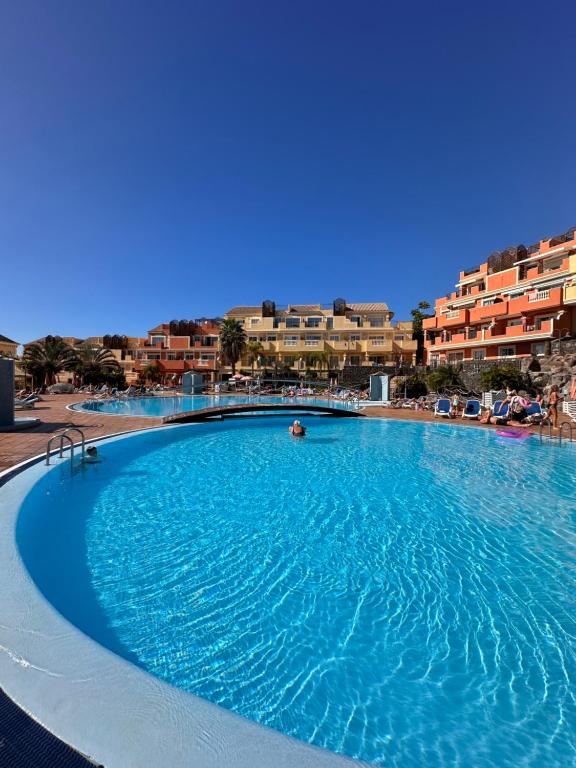 a large blue swimming pool with buildings in the background at Sunset Apartment & Heated Pool in Los Cristianos