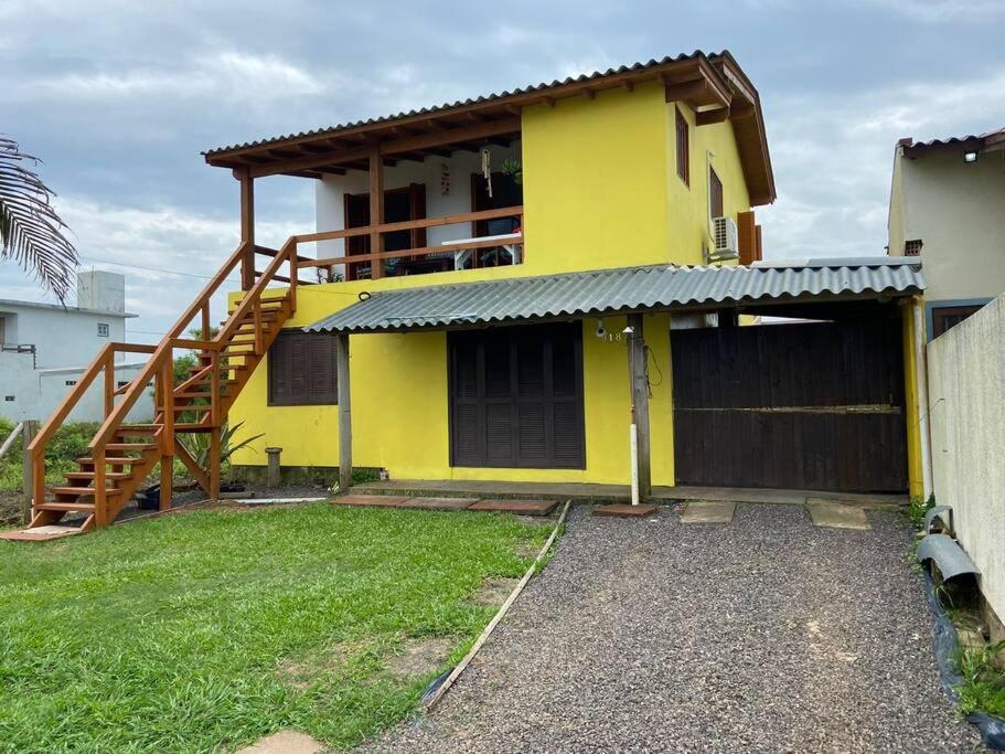 a yellow house with a staircase in front of it at Casa Amarela a Beira Mar entre Arroio do Sal e Torres in Arroio do Sal