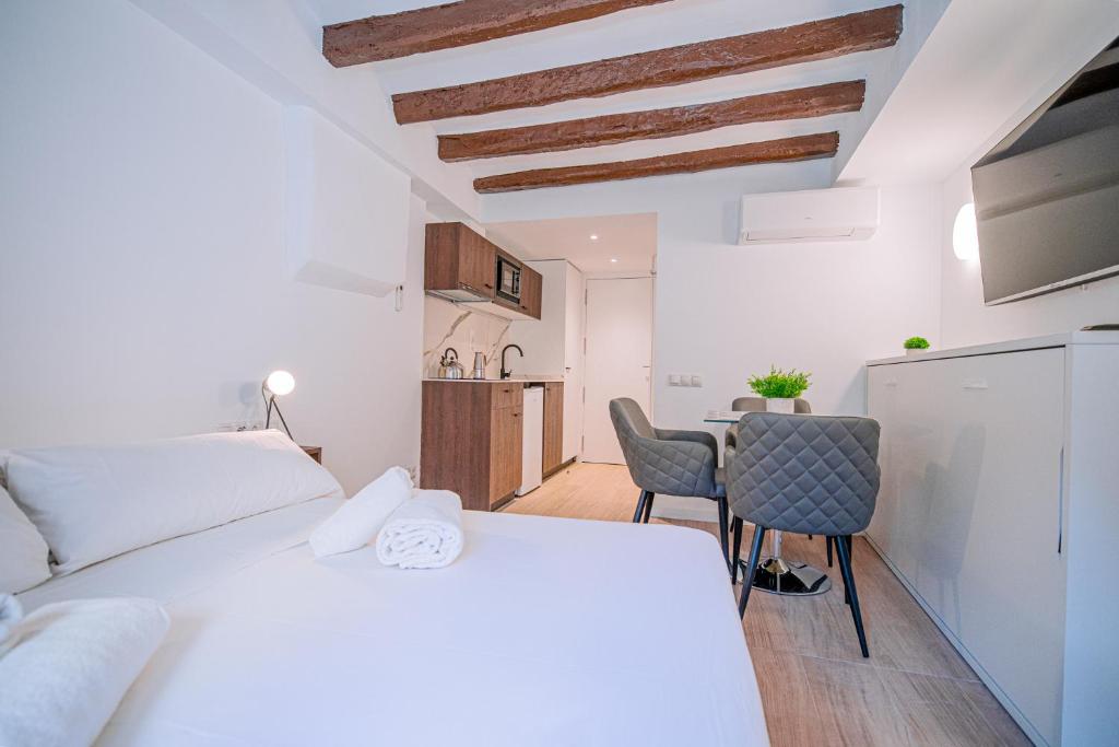 1 dormitorio con 1 cama blanca, mesa y sillas en ESTUDIO ROMAN & CATHEDRAL EXPERIENCe, en Tarragona