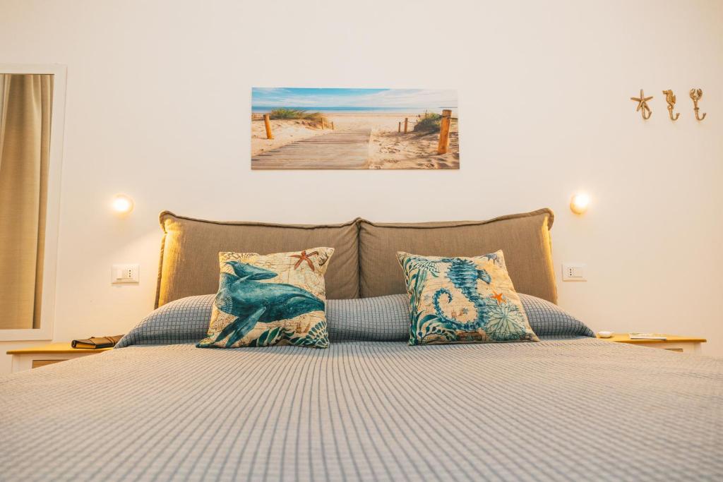 ein Bett mit Kissen und ein Bild von einem Strand in der Unterkunft Case Vacanze Il Sogno 2 in Porto Pino