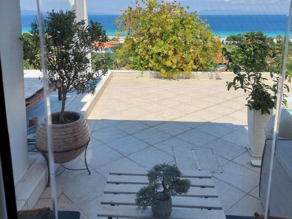 a patio with two potted trees and a view of the ocean at Seaview dreams in Ormos Panagias