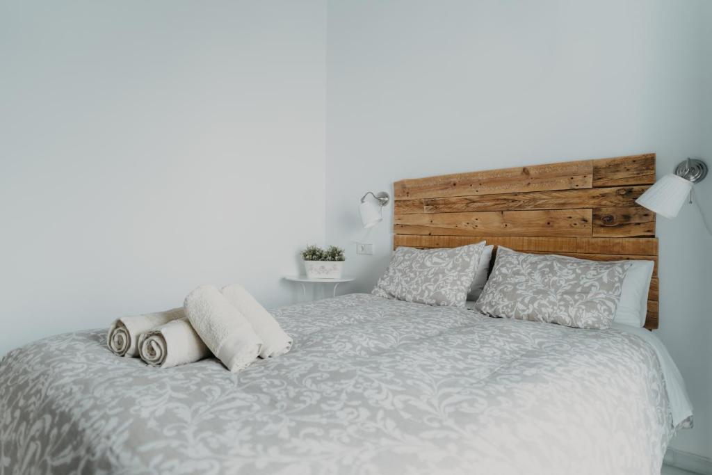 Schlafzimmer mit einem Bett mit einem Kopfteil aus Holz und Kissen in der Unterkunft Casa Palacio in Sanlúcar de Barrameda