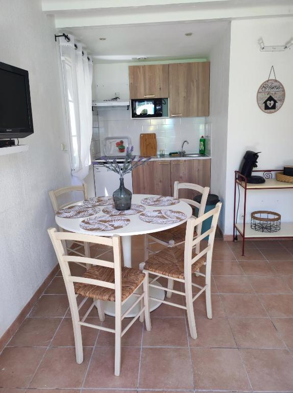 Il comprend une cuisine avec une table et des chaises blanches. dans l'établissement Jasse 632, à Gallargues-le-Montueux