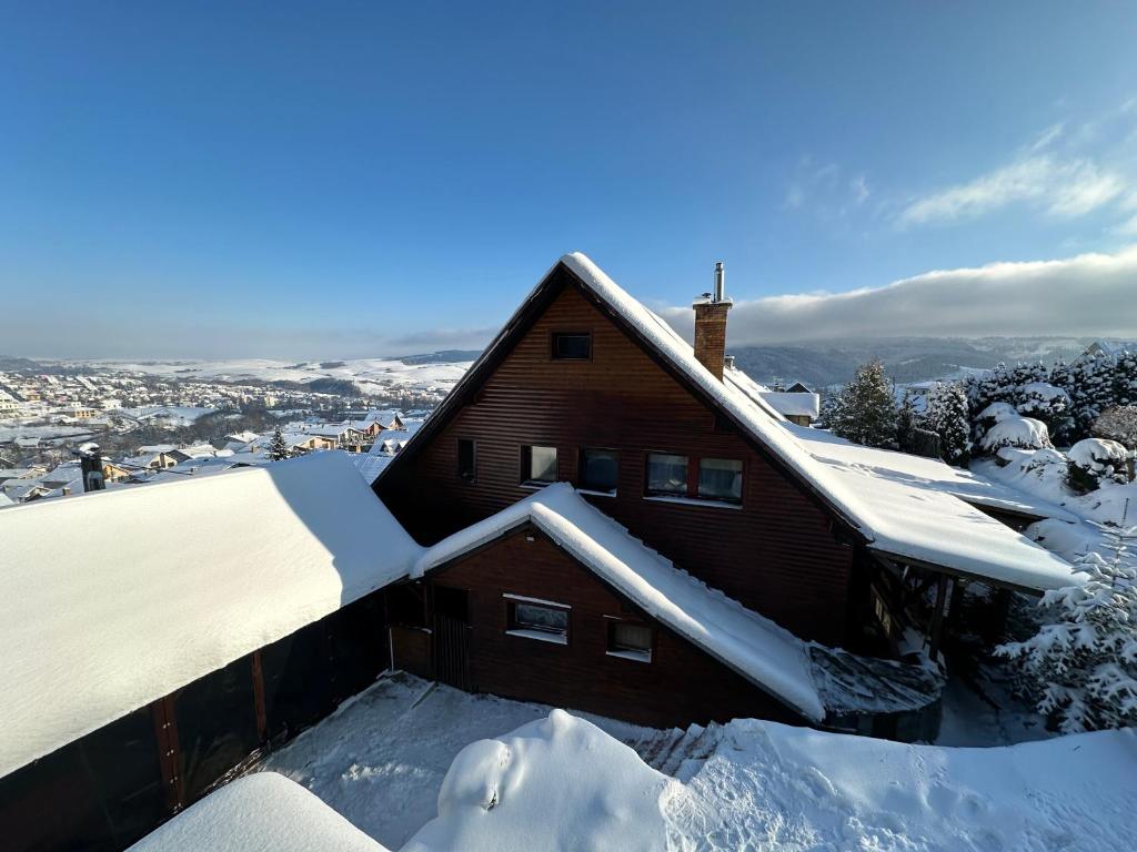 a house covered in snow with the city in the background at Ubytovanie Privat Antoni - apartmán v RD in Tvrdošín