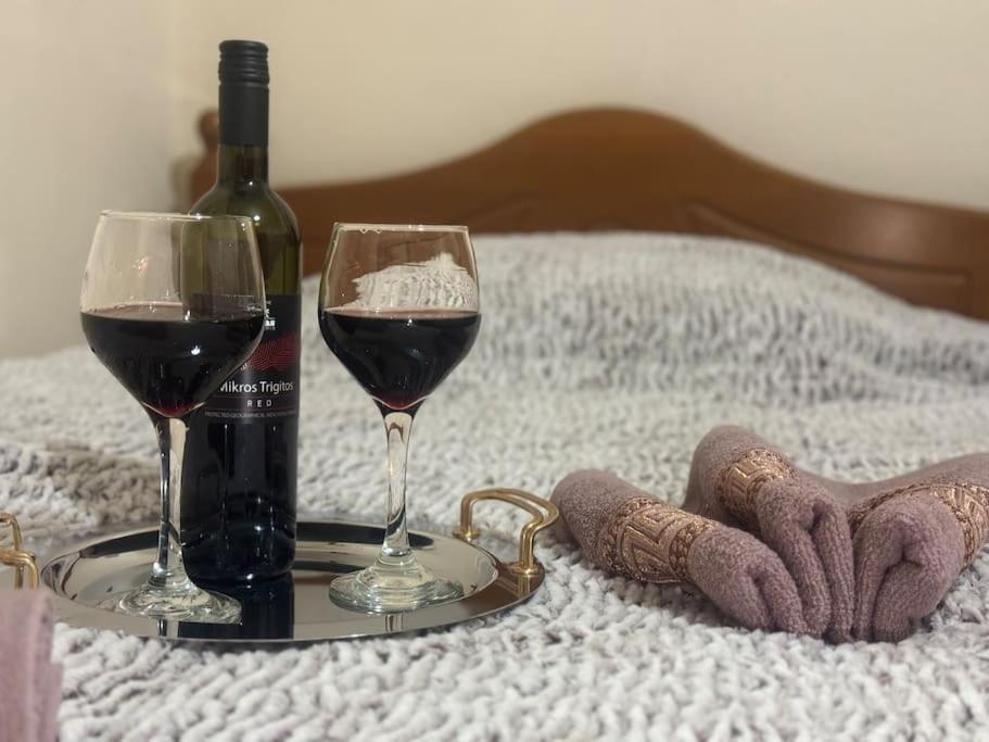 a tray with two glasses of wine on a bed at Gellis Village house Meteora in Kalabaka
