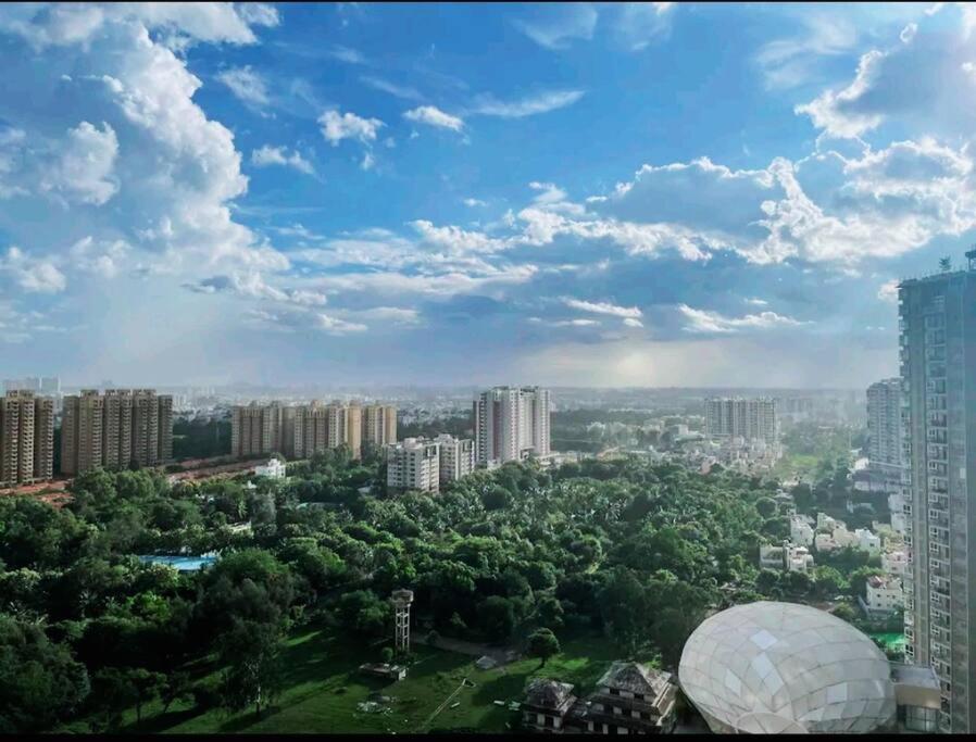 SOLACE Premium 2BHK Apartment near Manyata Tech Park And Hebbal في بانغالور: اطلالة على مدينة فيها مباني واشجار طويلة