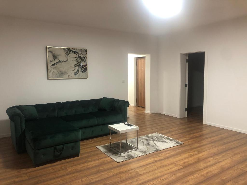 sala de estar con sofá verde y mesa en Gosen Apartaments en Sîngeorz-Băi