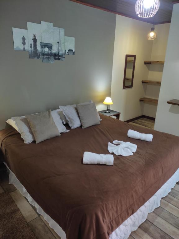 1 dormitorio con 1 cama grande y toallas. en Aconchego Do Lar, en Campos do Jordão