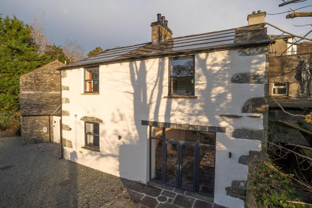 a white house with a shadow of a tree on it at New 4 Bedroom Home at Waterhead Range by LetMeStay in Ambleside