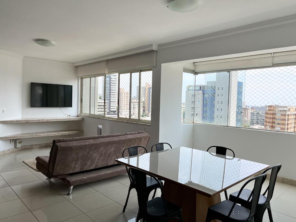 uma sala de estar com um sofá e uma mesa com cadeiras em Apartamento Centro/Sul BH em Belo Horizonte