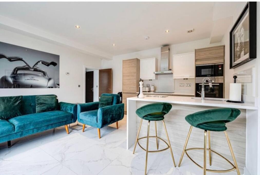 a living room with green chairs and a kitchen at Luxury Apartment: city centre, stylish, modern in Chester