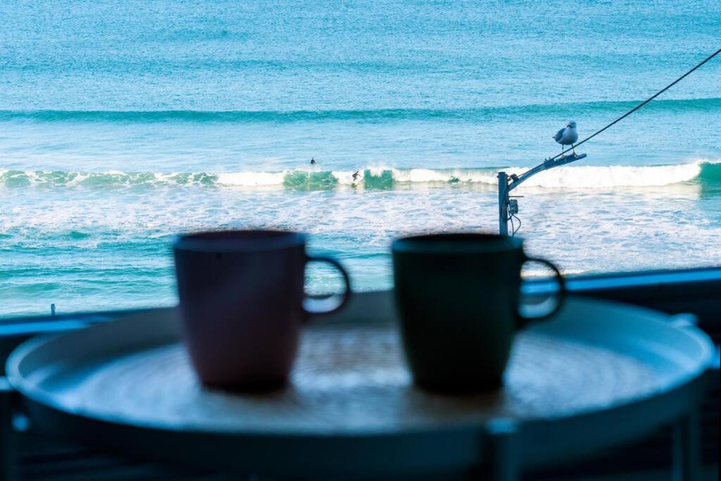 two coffee cups sitting on a table in front of the ocean at Apartamento Catuxa in Malpica