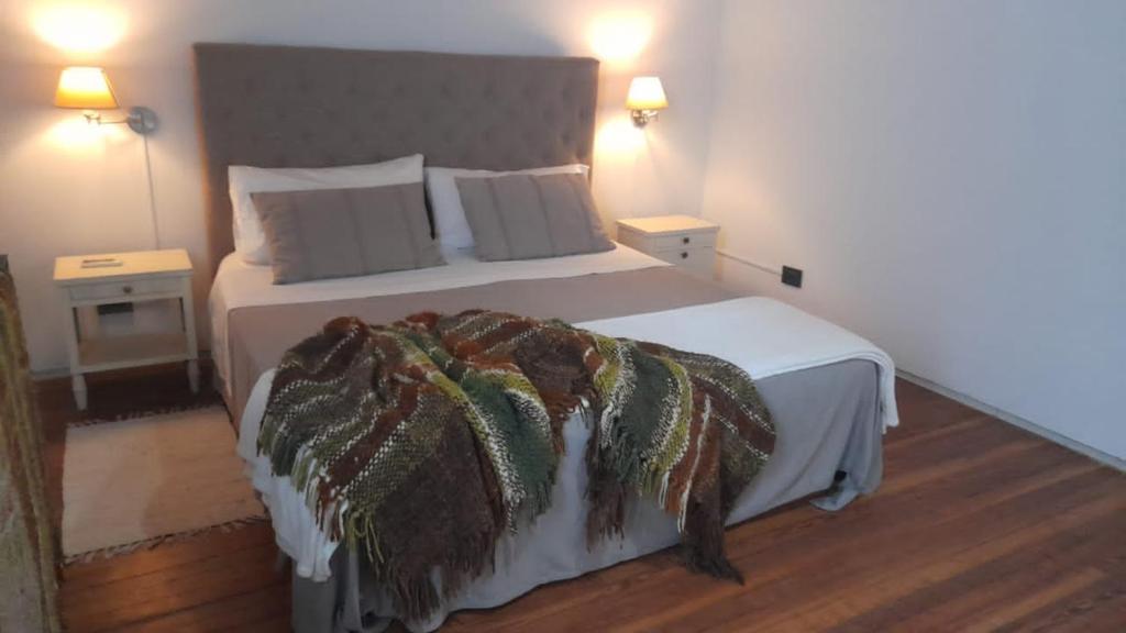a bedroom with a large bed with a blanket on it at Las Glicinas Boutique Apartments in Colonia del Sacramento
