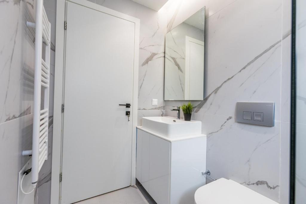 a white bathroom with a sink and a mirror at Varkiza Luxury Suites by Raise in Vari