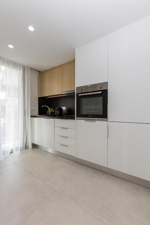 a kitchen with white cabinets and a microwave at Varkiza Luxury Suites by Raise in Vari