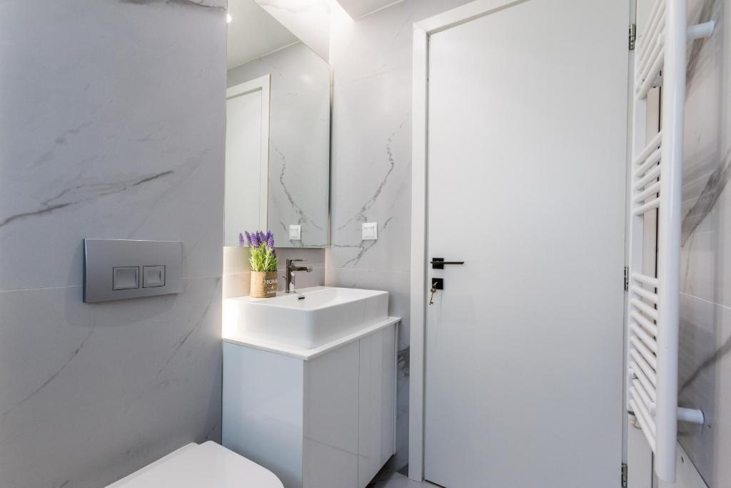 a white bathroom with a sink and a toilet at Varkiza Luxury Suites by Raise in Vari