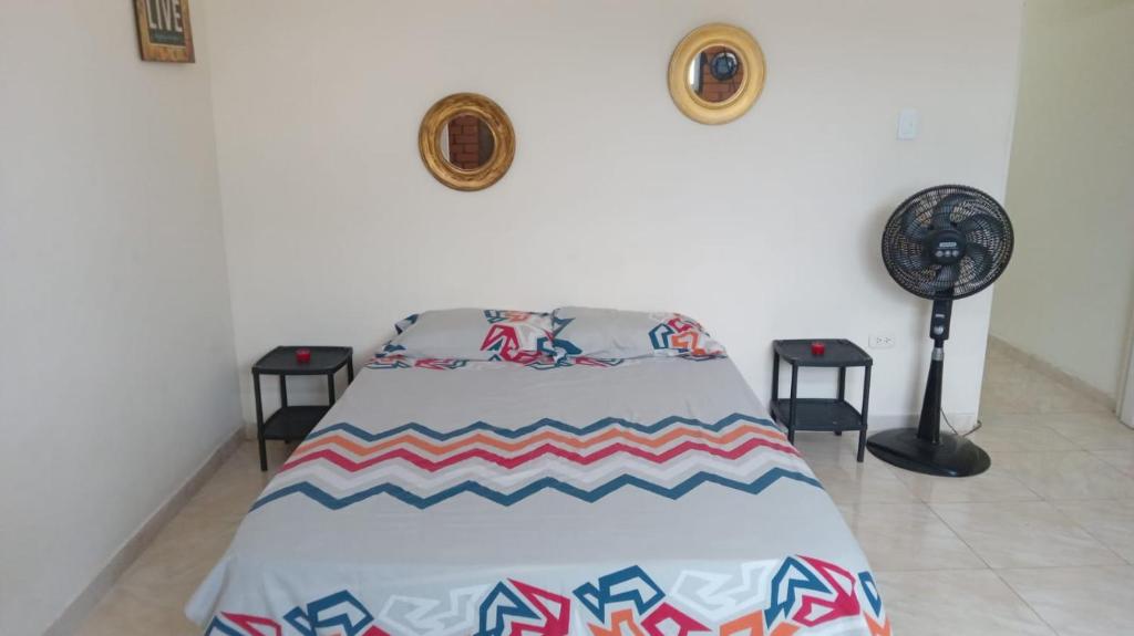 Cama en habitación con 2 mesas y ventilador en Apartaestudio en Tumaco, en Burrero