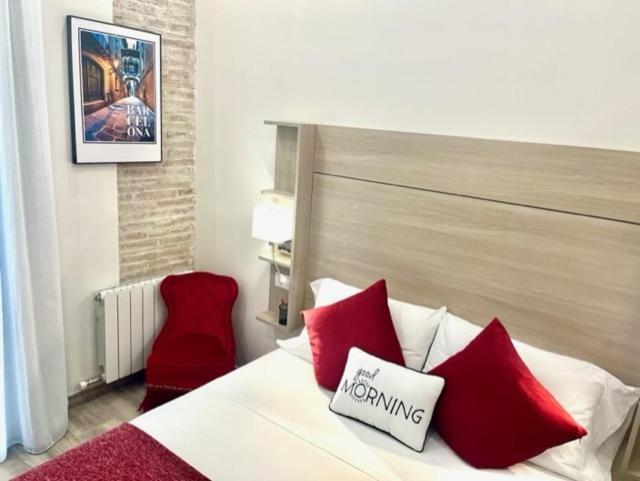 a bedroom with a bed with red pillows and a red chair at Front Arc in Barcelona