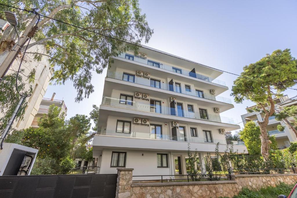 a tall white building with trees in front of it at Varkiza Luxury Suites by Raise in Vari
