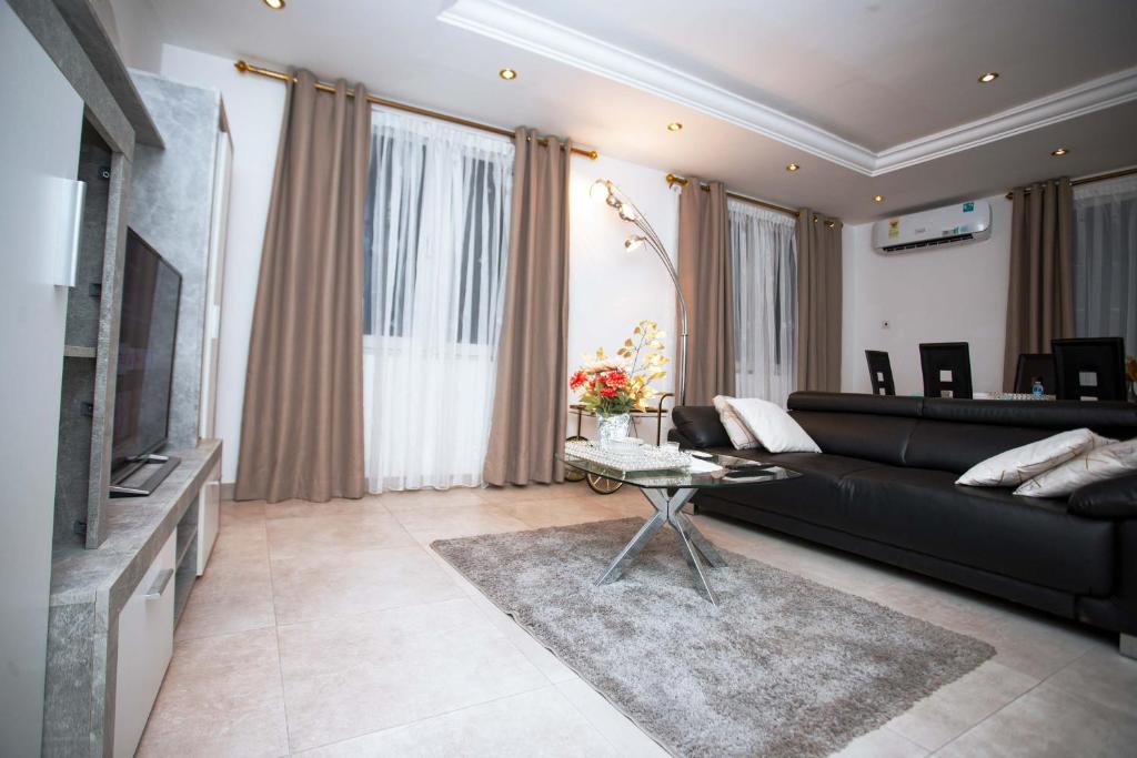un soggiorno con divano nero e tavolo di JQ Apartments a Accra