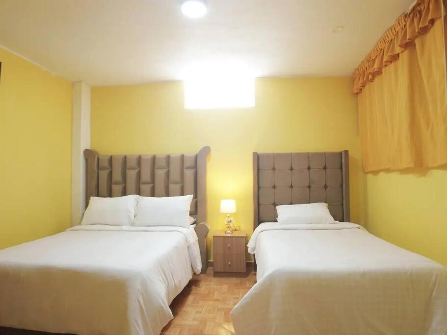 two beds in a room with yellow walls at Departamento Huanca in Huancayo