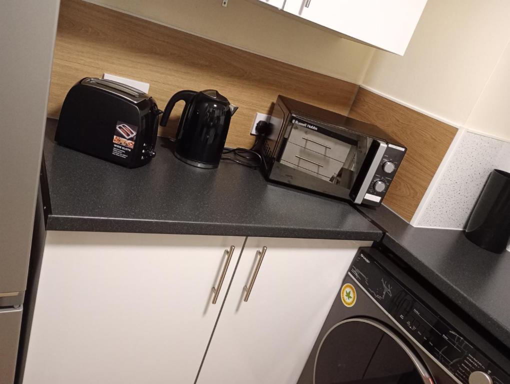 um balcão de cozinha com uma torradeira e um micro-ondas em The Diamond Hearts Apartments em Milton Keynes