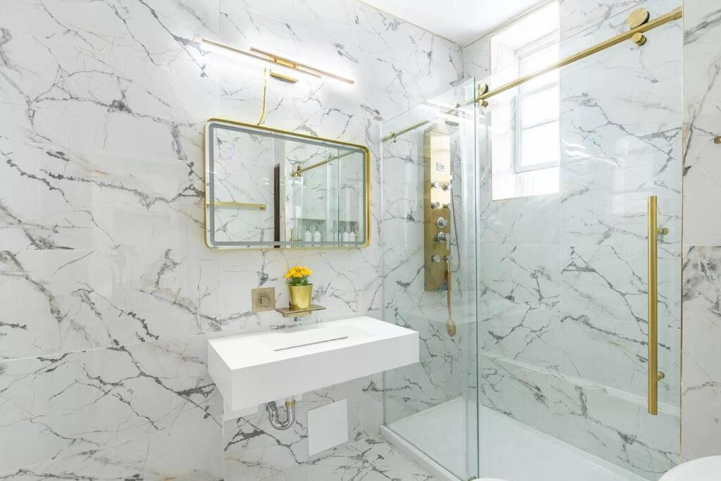 a white bathroom with a sink and a mirror at Luxury Living in the Heart of NY! in Yonkers