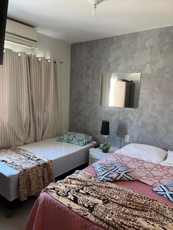 a bedroom with two beds and a mirror on the wall at Casa para Temporada Lençóis Ville in Barreirinhas