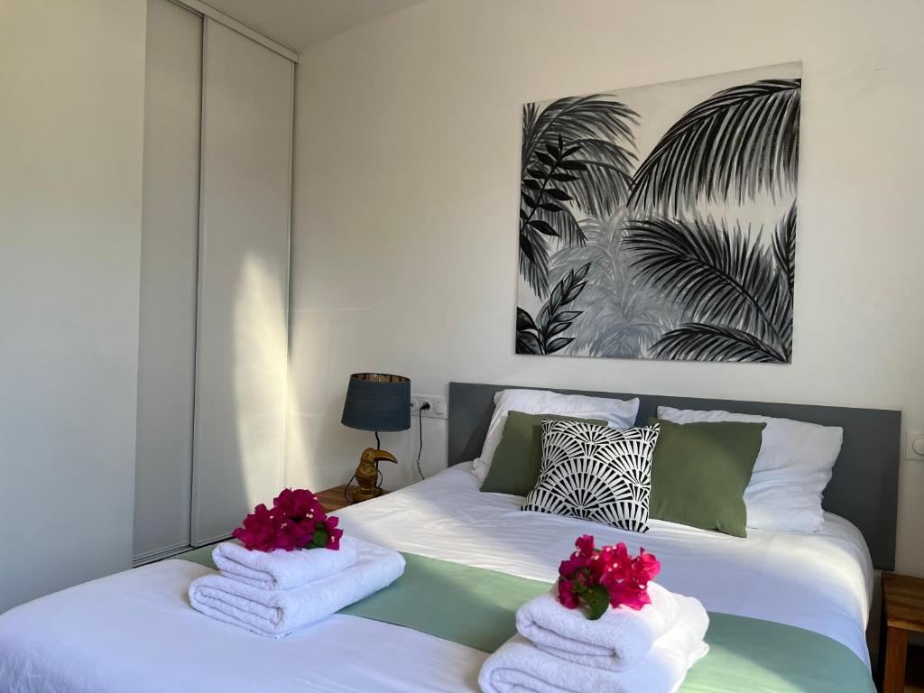 um quarto com uma cama com toalhas e flores em Bungalow cosy près des plages em Le Gosier