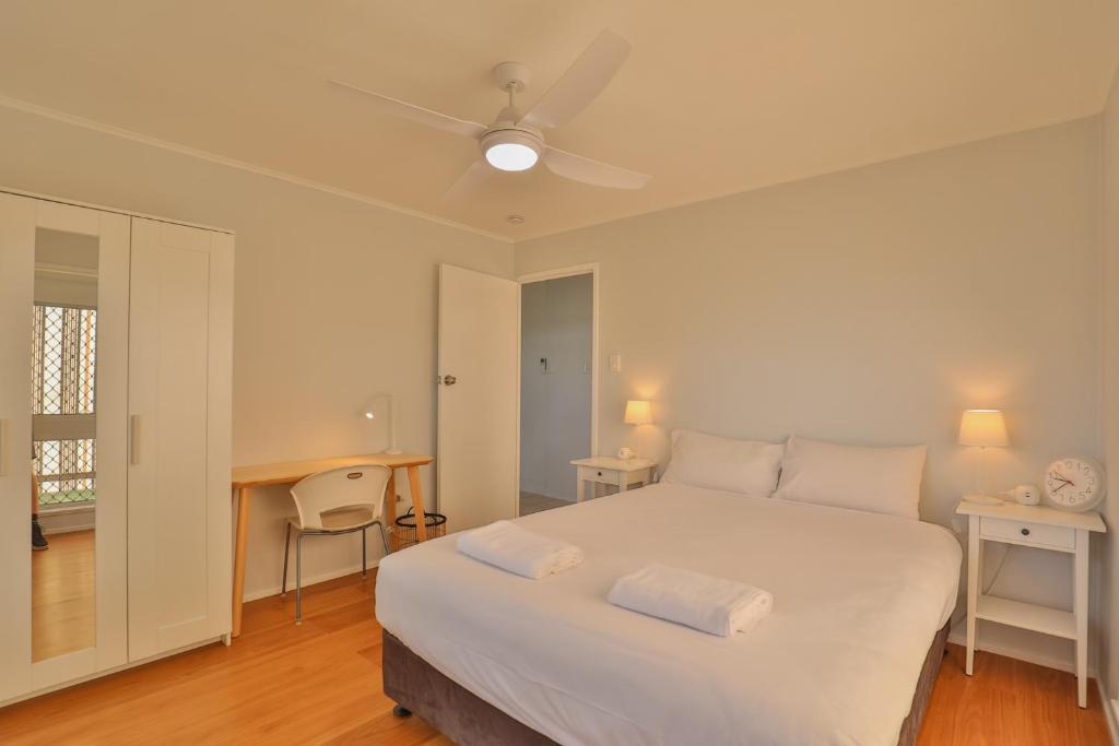 a bedroom with a large white bed and a desk at Pacific Sun Bargara in Bargara